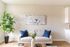 Chic living room with a cozy beige sofa, vibrant blue cushions, elegant floral artwork, and a lush green plant, perfect for relaxation.