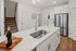 Sleek modern kitchen with stainless steel appliances, pristine white cabinets, and elegant wooden flooring, offering a warm and inviting atmosphere.