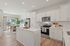 Modern kitchen with sleek white cabinets, stainless steel appliances, and a spacious island, seamlessly connected to a bright dining area with large windows overlooking a lush garden.
