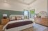 Inviting bedroom with elegant decor, warm wooden furniture, and ample natural light pouring through large windows.