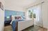 Bright and inviting bedroom with elegant blue accent wall, large window, and plush bedding.