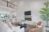 Modern living room with vaulted ceilings, cozy fireplace, and open kitchen featuring sleek cabinets, island seating, and lush greenery accents.