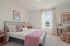 Bright and cozy bedroom featuring a stylish bed with plush pillows, soft lighting, and a serene window view.