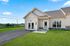 Charming suburban home with modern exterior, inviting lawn, and scenic countryside views.