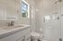Bright and modern bathroom with sleek glass shower, large window, and elegant vanity.