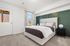 Bright and inviting bedroom with a modern upholstered bed, elegant green accent wall, and cozy natural light.