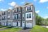 Modern multi-story townhouse with elegant gray siding, multiple large windows, and attached garages in a serene neighborhood setting.