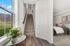 Inviting apartment entrance with sleek wooden flooring, a charming staircase, and a glimpse of a cozy bedroom with elegant bedding and stylish decor.