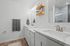 Bright and modern bathroom with dual marble sinks, sleek fixtures, and elegant wooden shelving.