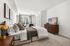 Bright, inviting bedroom featuring chic modern decor, plush bedding, and a sunlit window overlooking stylish townhomes.