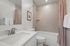 Modern bathroom with a sleek white vanity, elegant brushed nickel faucet, and a chic tiled bathtub featuring a stylish shower curtain.