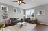 Bright and welcoming living room featuring modern gray sofas, large windows, hardwood floors, and stylish decor with abundant natural light.