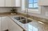 Elegant kitchen with granite countertops, double stainless steel sink, and a bright window view.