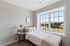 Inviting bedroom with a large window showcasing scenic views, featuring a cozy bed, modern decor, and ample natural light.
