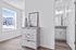 Bright and airy apartment hallway with elegant wooden flooring, featuring a chic dresser and modern decor, showcasing a glimpse into a stylish bathroom.