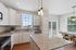 Bright and modern kitchen with elegant granite countertops, sleek white cabinetry, and a cozy dining area with large windows offering scenic views.