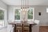 Bright dining area with elegant pendant lighting, large windows offering lush garden views, and comfortable seating around a stylish wooden table.