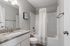 Bright modern bathroom with elegant granite countertops, stylish fixtures, and a sleek shower-tub combo.
