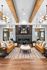 Chic living room with elegant wooden beams, modern chandeliers, and cozy seating area around a sleek fireplace.