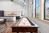 Modern game room with stylish shuffleboard table, sleek kitchen bar, and panoramic windows offering natural light.