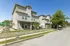 Modern three-story townhouses on a sunny residential street, showcasing contemporary design and a peaceful neighborhood.