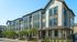 Modern townhouse complex with elegant facades, featuring large windows and inviting front porches, set in a tranquil neighborhood.