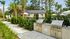 Lush outdoor BBQ area with modern grill stations surrounded by greenery and palm trees, perfect for entertaining.