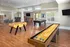 Elegant billiards room featuring a pool table, foosball table, and shuffleboard table. The space includes additional seating areas for relaxation or socializing at Abberly Place Apartments in Garner, NC