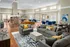 Bright and inviting resident activity center featuring a stone double-sided fireplace, multiple seating areas and large windows allowing natural light to flow in at Abberly Place Apartments in Garner, NC
