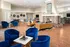 Spacious resident clubhouse featuring a double-sided stone fireplace, cozy seating areas, hardwood flooring, a dining table, and a bar area with high-top seating at Abberly Place Apartments in Garner, NC