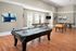 Spacious game room featuring a variety of recreational options, including a pool table, shuffleboard, and foosball table at Abberly Place Apartments in Garner, NC