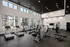 A gym featuring cardio equipment and weights, located in a building with large windows that allow natural light to flood the space at Abberly Liberty Crossing Apartments in Charlotte, NC