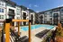 Modern apartment complex with a pool, lounge chairs, and umbrellas under a clear blue sky at Abberly Liberty Crossing Apartments in Charlotte, NC