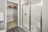 A modern bathroom featuring sleek fixtures, a walk-in shower, a sink, and a toilet. The space also includes a walk-in closet, providing ample storage and convenience at Abberly Liberty Crossing Apartments in Charlotte, NC