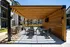 Patio with grills, tables, chairs, and a wooden privacy wall at Abberly Liberty Crossing Apartments in Charlotte, NC