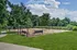Fenced on-site dog park featuring a spacious play area with mulch ground cover, two benches for pet owners, and surrounded by lush greenery at Abberly Woods Apartment Homes in North Carolina