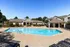Outdoor swimming pool surrounded by a spacious deck with lounge chairs. The pool is bordered by a well-maintained landscape, with a clubhouse and a covered seating area at Abberly Woods Apartment Homes in Charlotte, NC
