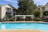 Poolside pergola, providing a shaded seating area with lounge chairs, surrounded by lush greenery and overlooking a crystal-clear swimming pool at Abberly Woods Apartment Homes in Charlotte, NC