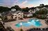 Aerial view of the outdoor pool area at dusk, featuring a resort-style pool with ample lounge seating, and the community clubhouse surrounded by well-maintained landscaping at Abberly Woods Apartments in Charlotte, NCat Abberly Woods Apartments in Charlotte, NC