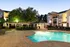 Outdoor swimming pool with a large patio area during dusk, surrounded by lounge seating, trees with soft evening lighting, and adjacent to apartment buildings at Abberly Woods Apartments in Charlotte, NC