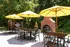 A patio with yellow umbrellas and a grill with an outdoor fireplace at Abberly Twin Hickory Apartments in Glen Allen, VA