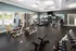 A large fitness room with cardio equipment and a pool in the background at Abberly Twin Hickory Apartments in Glen Allen, VA
