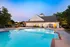 A swimming pool with lounge chairs and umbrellas at dusk at Abberly Twin Hickory Apartments in Glen Allen, VA