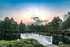 A white bridge over a pond with a sunset in the background at Abberly Twin Hickory Apartments in Glen Allen, VA