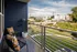 A balcony with a chair, a potted plant, and a view of the city at Abberly Noda Vista Apartments in Charlotte, NC