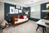 A bedroom with navy blue walls and a white bedspread with red pillows at Abberly Noda Vista Apartments in Charlotte, NC