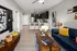 A living room with a blue couch and coffee table, and a kitchen in the background at Abberly Noda Vista Apartments in Charlotte, NC