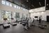 A gym featuring cardio equipment and weights, located in a building with large windows that allow natural light to flood the space at at Abberly Alston Apartment Homes and Townhomes in Cary, NC