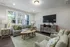 A living room with a couch, table, chairs, and a TV mounted on the wall at Abberly Alston Townhomes in Cary, NC