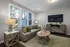 A living room with a couch, table, chairs, and a TV mounted on the wall at Abberly Alston Townhomes in Cary, NC